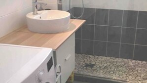 A compact bathroom with a sink, a washing machine, and a shower area. - Apartment Cosy annemasse (Annemasse)