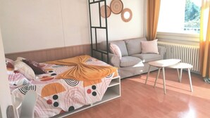 A room with a bed, a sofa, a small table, and a radiator. - Apartment Cosy annemasse (Annemasse)