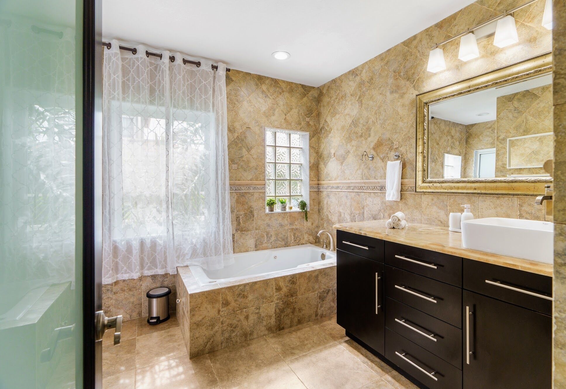 A modern bathroom with a bathtub, a large mirror, and a vanity with a sink.