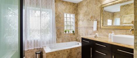 A modern bathroom with a bathtub, a large mirror, and a vanity with a sink.