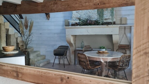 Un comedor rústico con una mesa redonda y sillas de mimbre, una pared de piedra y un techo de madera.