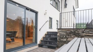 A modern building with a glass door leading to a patio area. - Garth Hill House (Ambleside)