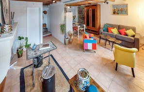 A modern living room with a sofa, a coffee table, and a dining area with a table and chairs. - Cottage 'La Cassine' with Shared Terrace, Shared Garden and Wi-Fi (Taillant)