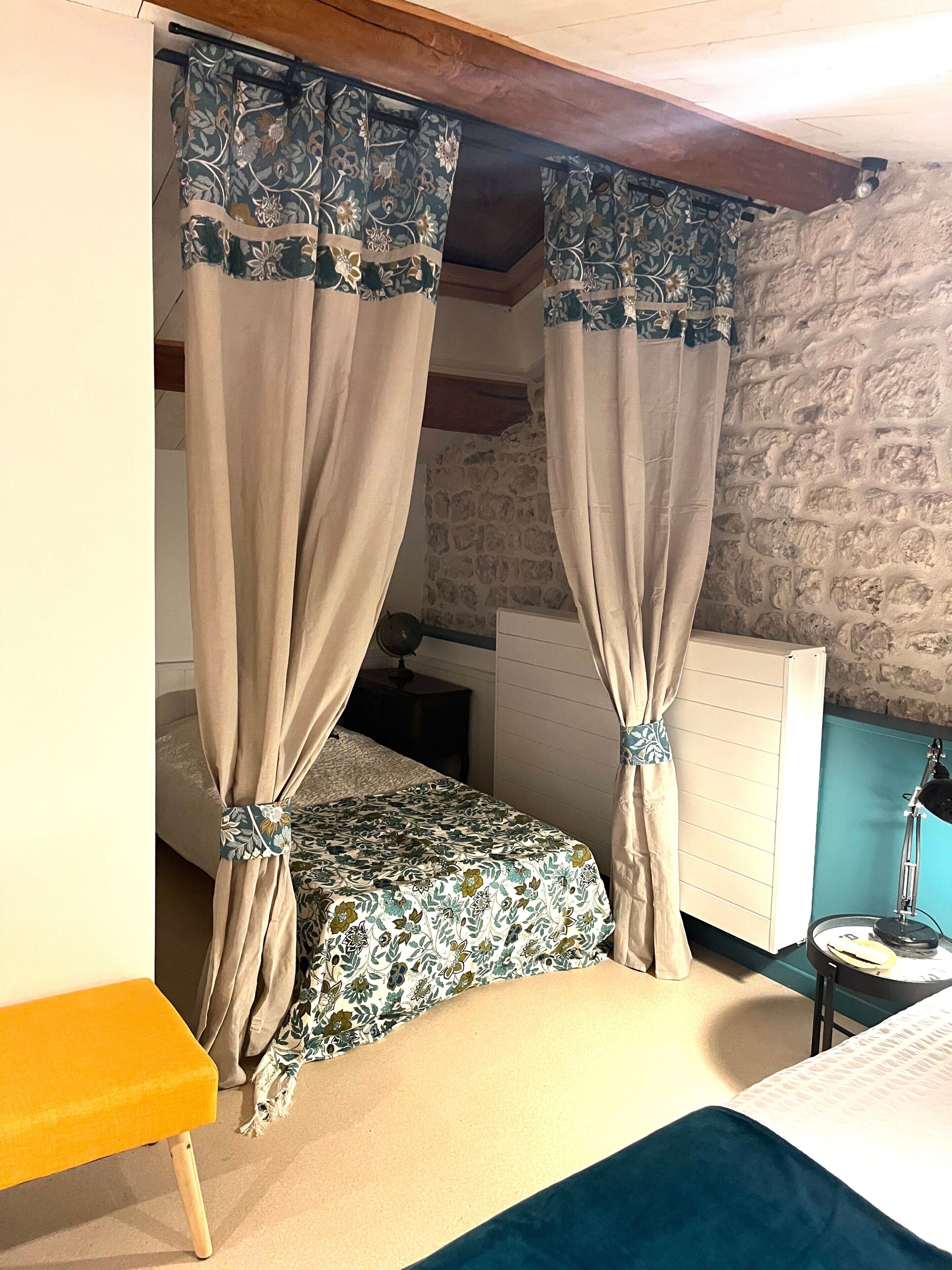 Un dormitorio con cama, mesita de noche, lámpara y pared de piedra.