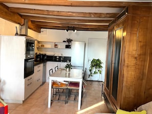 A kitchen with wooden beams, a dining table with chairs, a refrigerator, and a sink. - Cottage 'La Cassine' with Shared Terrace, Shared Garden and Wi-Fi (Taillant)