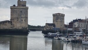 Eine historische Burg aus Stein mit einem Burggraben, ein kleines Boot liegt in der Nähe und ein ruhiges Gewässer spiegelt die Gebäude wider.