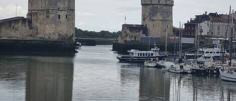 A historic stone castle with a moat, a small boat docked nearby, and a calm water body reflecting the structures.