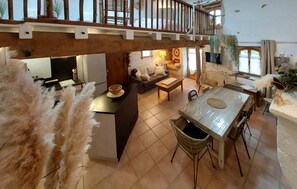 A spacious living area with a balcony, a dining table, and a sofa. - Cottage 'Gîte La Baragane' with Shared Terrace, Shared Garden and Wi-Fi (Taillant)