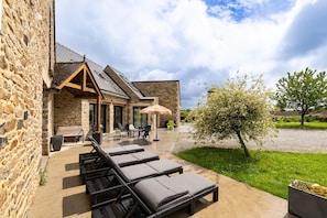 Un edificio de piedra con un patio que cuenta con sillones y una mesa.