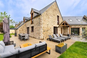 Una casa in pietra con patio, mobili da esterno e giardino.
