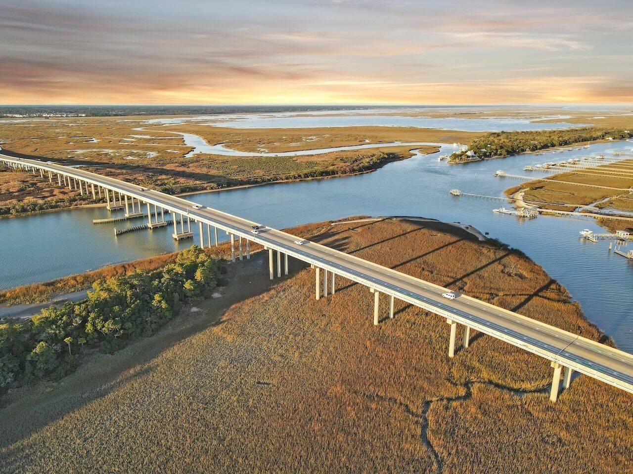 A long bridge over a river with a flat landscape and sparse vegetation.