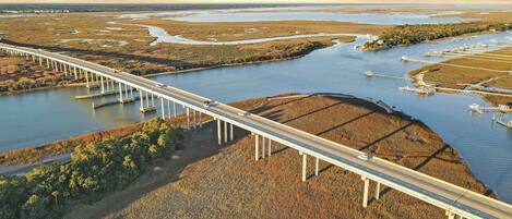 A long bridge over a river with a flat landscape and sparse vegetation.