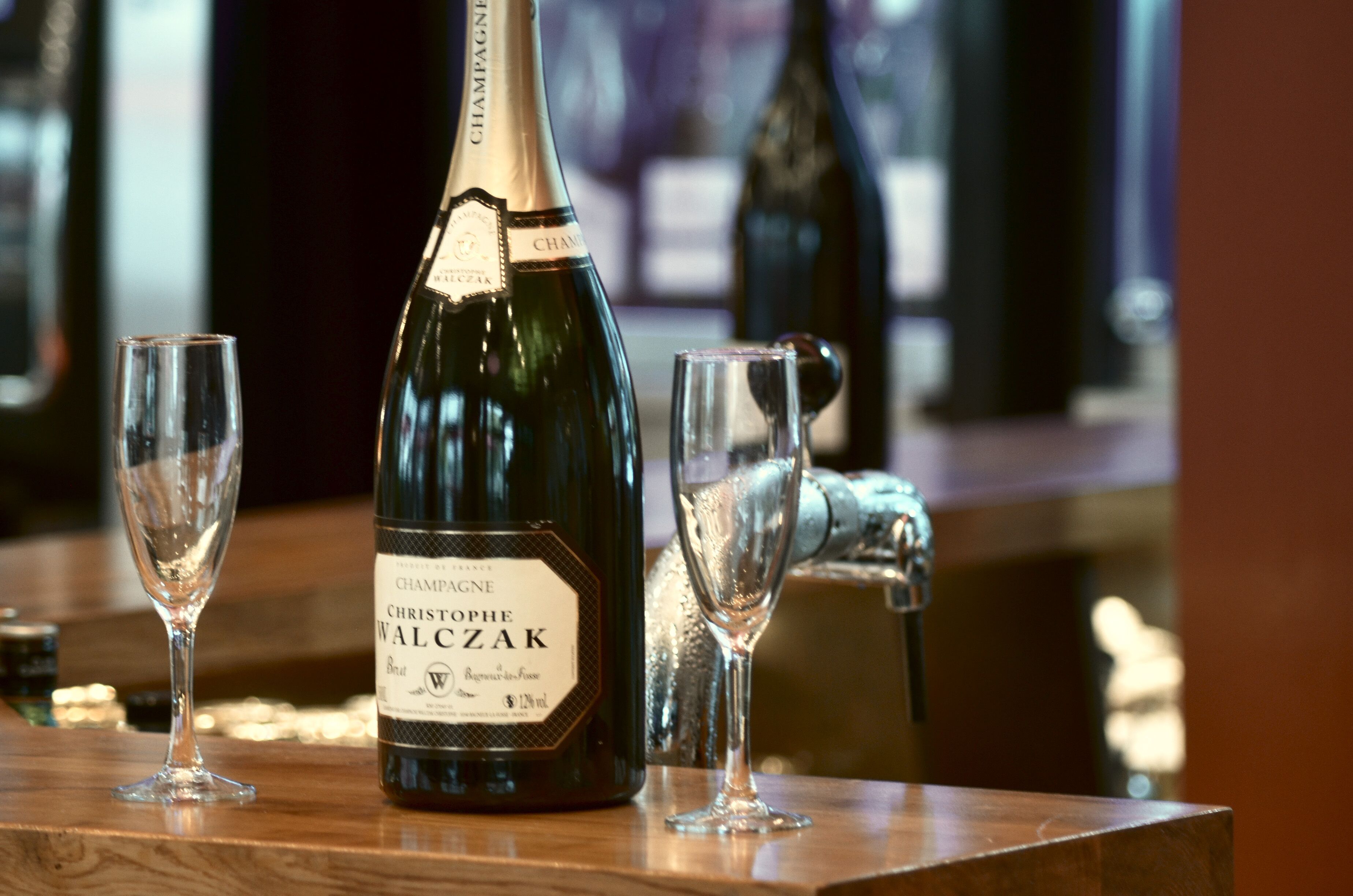 A bottle of Champagne Christophe Walczak on a bar counter with two glasses.