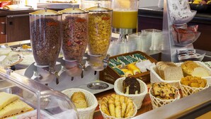 Un bufé con diversos alimentos, entre ellos cereales, pan y pasteles.