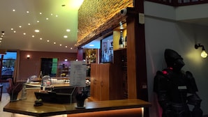 Una zona de bar con estantes de madera, una pizarra de menú y una cámara de seguridad.