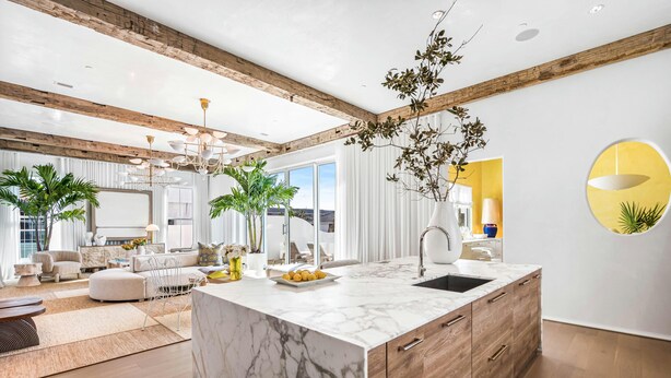 A modern kitchen with a marble island, wooden cabinets, and a large window. - Official 30A Show House with Private Pool, Elevator, Putt Putt, Private Beach (Rosemary Beach)