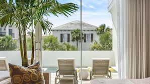 A balcony with a pool, lounge chairs, and a palm tree. - Official 30A Show House with Private Pool, Elevator, Putt Putt, Private Beach (Rosemary Beach)