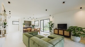 A modern living room with a sectional sofa, a dining area, a kitchen, and a TV. - Villa 'Artylino' with Private Pool, Wi-Fi and Air Conditioning (Lazise)