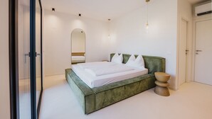 A modern bedroom with a green upholstered bed, a large mirror, and a wooden side table. - Villa 'Artylino' with Private Pool, Wi-Fi and Air Conditioning (Lazise)
