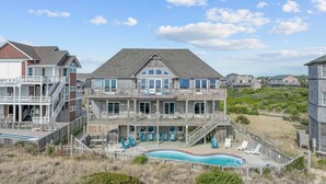 A large two-story house with a balcony, a swimming pool, and beach views. - Oceanfront w/ Pool, Hot Tub, Elevator, Game Room. Feel like an Island Princess! (Frisco)