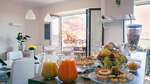 Ein reichhaltiges Frühstücksbuffet mit Gebäck, Früchten und einem Orangensaftkrug auf einer Theke.
