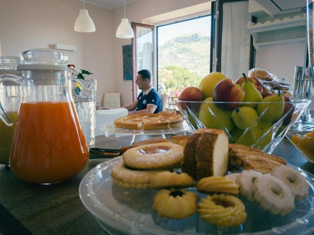Un buffet de petit-déjeuner comprenant des viennoiseries, des fruits et une carafe de jus d’orange.