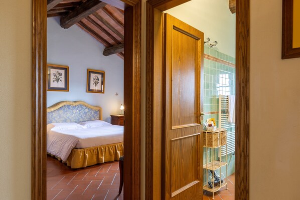 A bedroom with a bed, a nightstand, and a wall-mounted shelf.