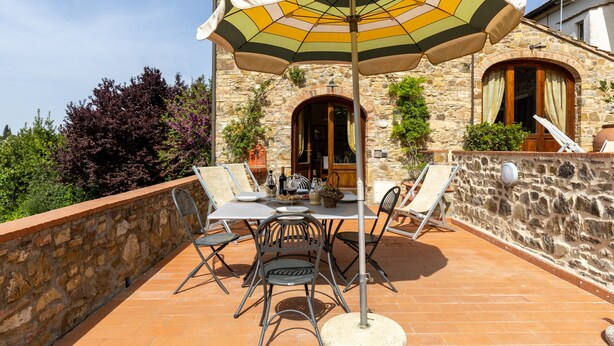 Eine Terrasse im Freien mit Tisch, Stühlen und einem großen Sonnenschirm.
