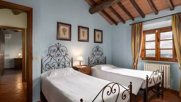 Una camera da letto con due letti, soffitto in legno e finestra con tende.