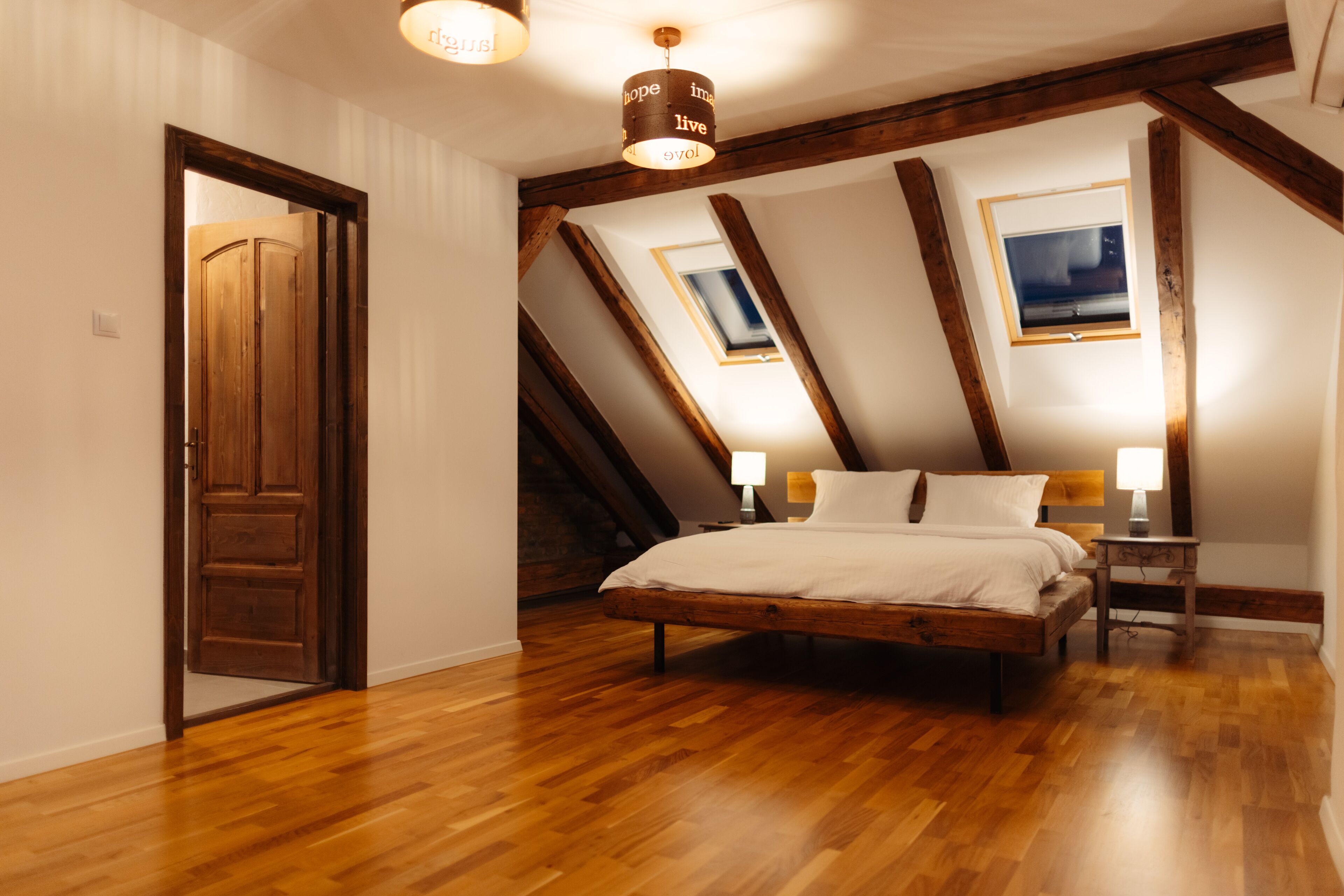 A bedroom with a wooden bed, sloped ceiling, and skylights.