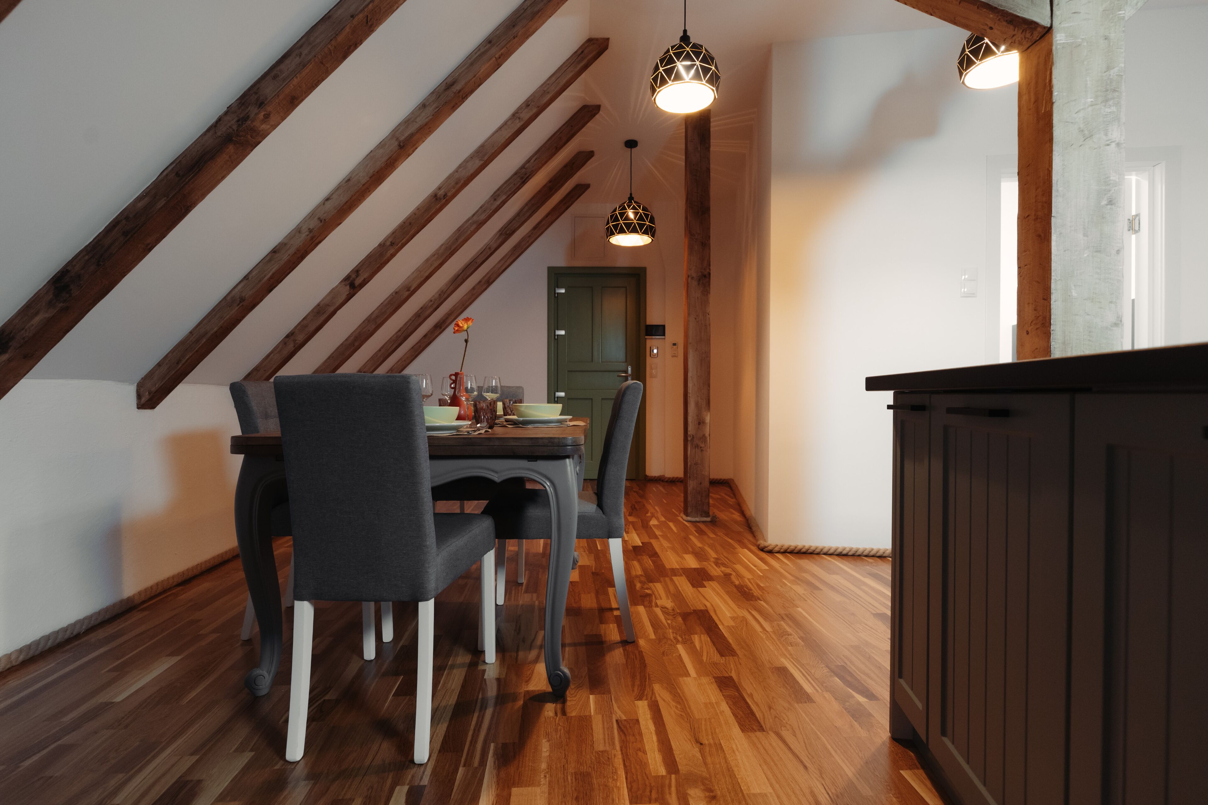 A dining area with a wooden ceiling, a table with chairs, and pendant lighting.