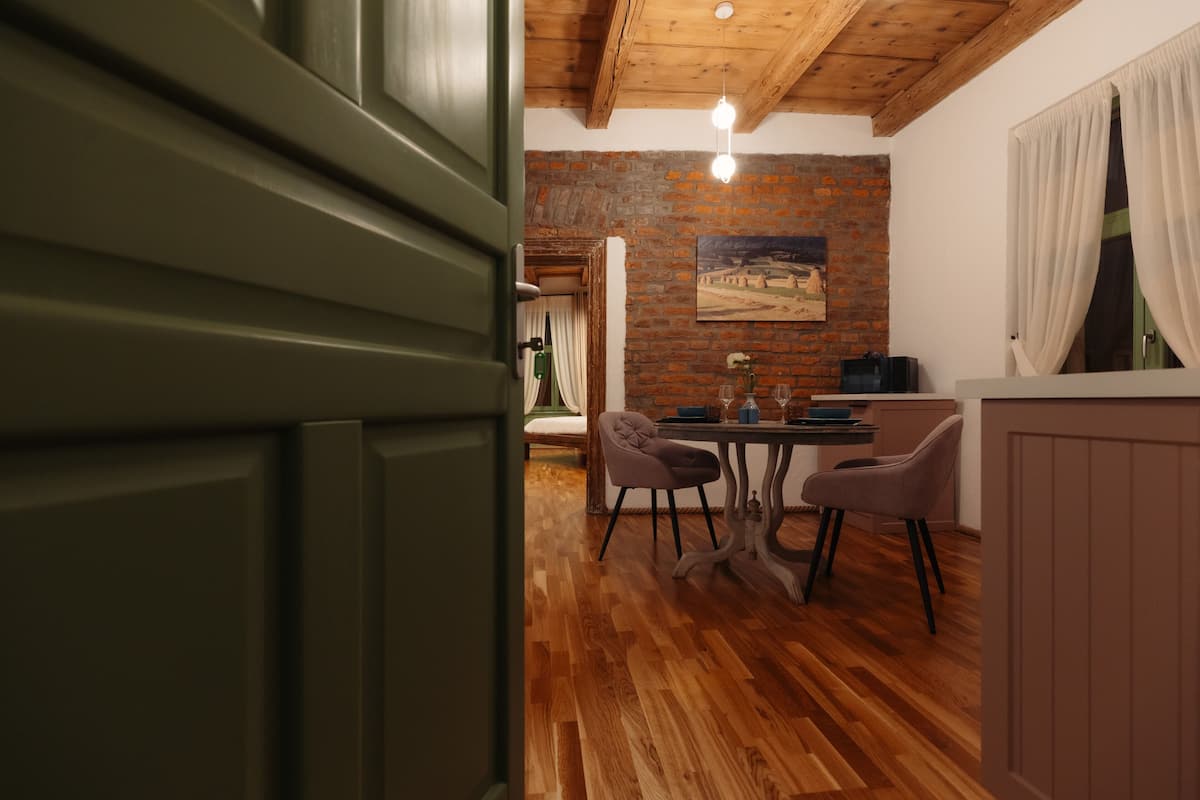 A dining area with a brick wall, wooden floor, and a painting above the table.