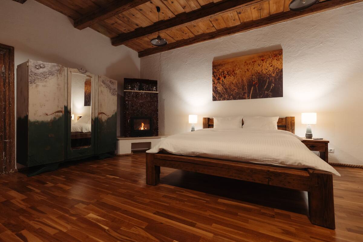 A bedroom with a wooden bed, a fireplace, and a painting on the wall.