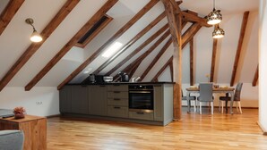 Une cuisine moderne avec des poutres en bois, un coin repas avec des chaises et un plancher en bois.