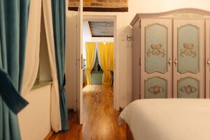 Un pasillo que conduce a un dormitorio con suelo de madera, una cama y un armario con paneles decorativos.