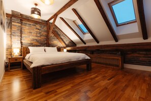 Une chambre avec un lit en bois, un mur en briques et une lucarne.