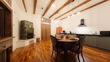 A dining area with a wooden table and chairs, a fireplace, and a kitchen in the background.