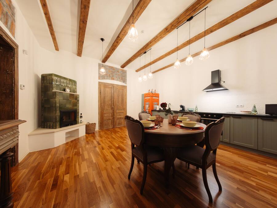 A dining area with a wooden table and chairs, a fireplace, and a kitchen in the background.