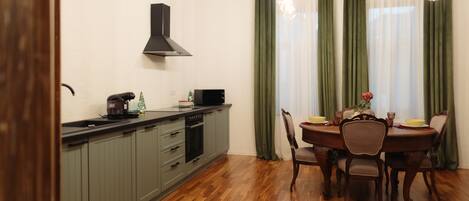 Una cocina con armarios grises, una campana extractora negra y una zona de comedor con una mesa y sillas de madera.