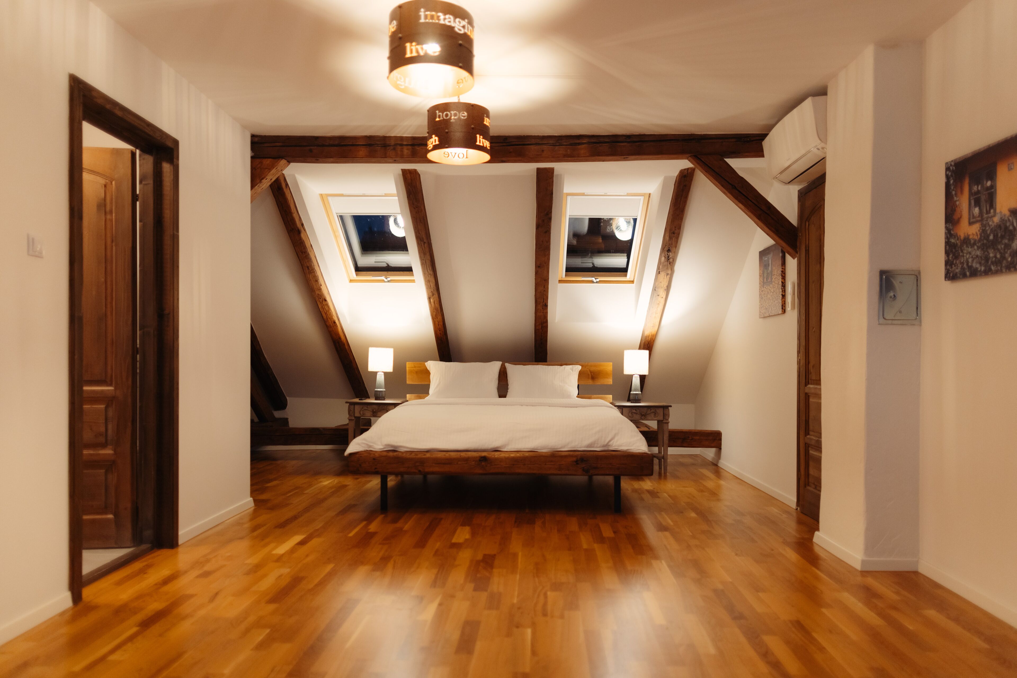 Un dormitorio con cama de madera, tragaluces y lámpara en el techo.
