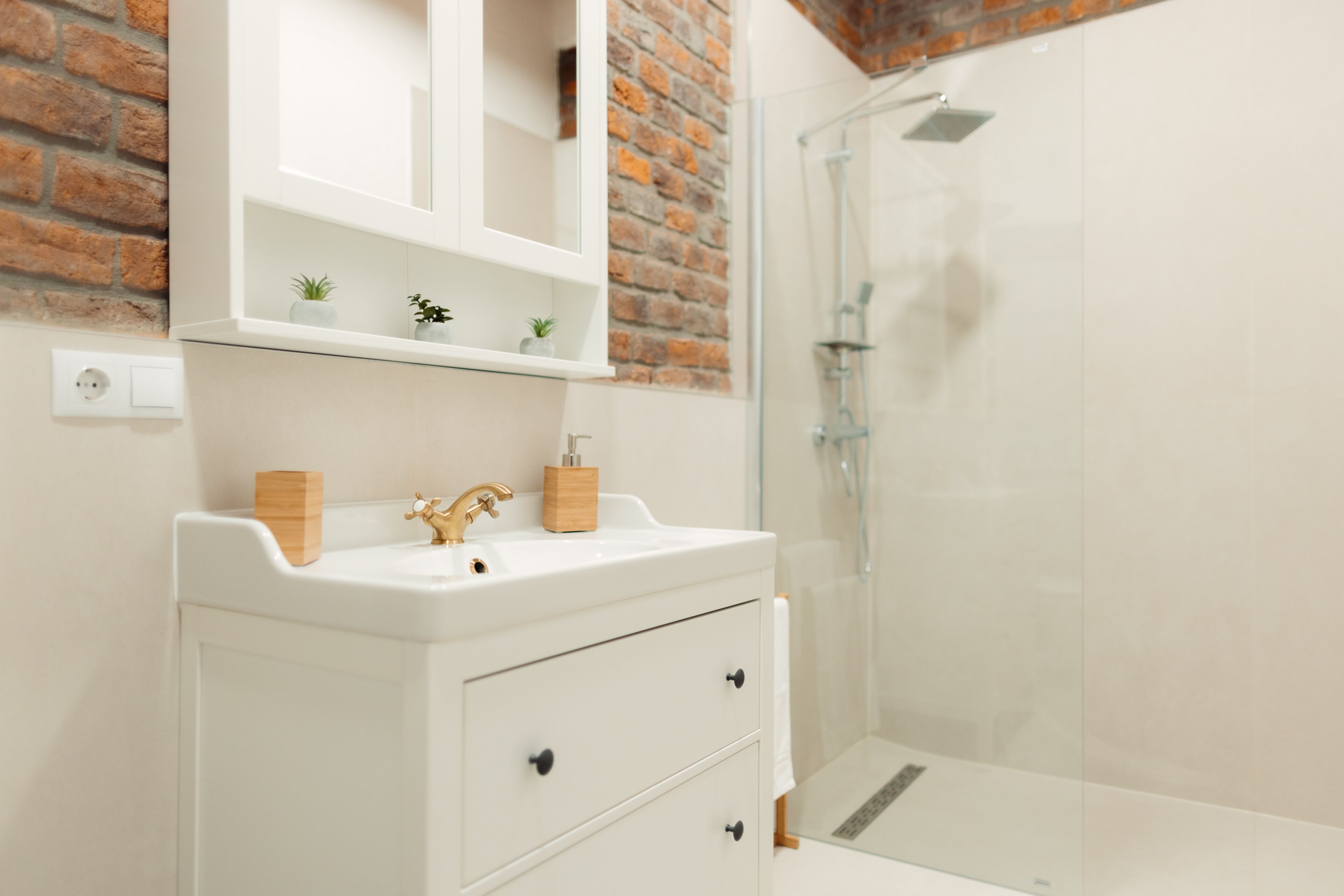 A bathroom with a white sink, wooden cabinet, and a glass shower enclosure.