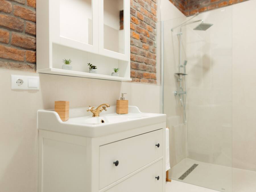 A bathroom with a white sink, wooden cabinet, and a glass shower enclosure.