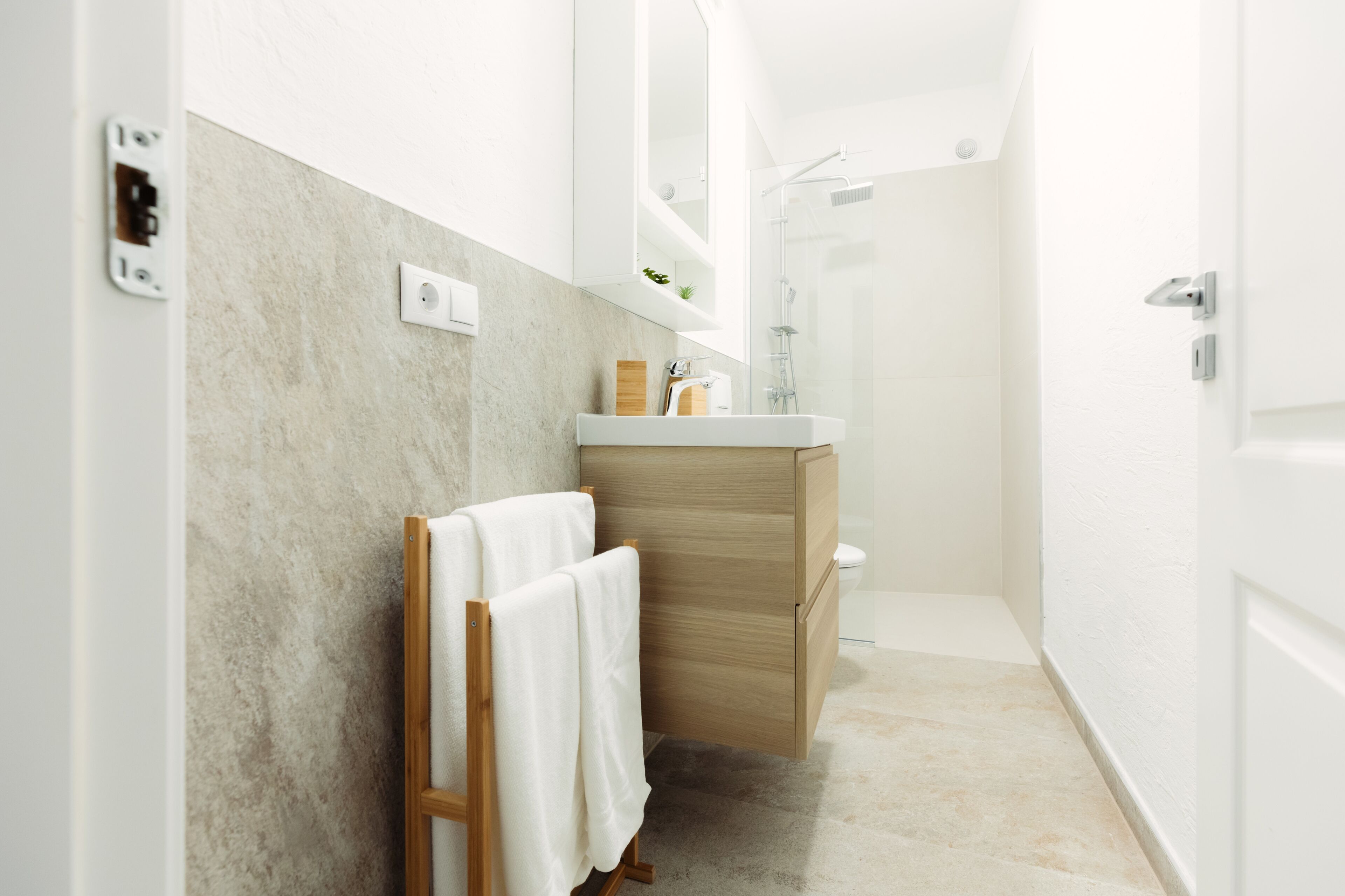 Un baño moderno con tocador de madera, ducha y perchero.