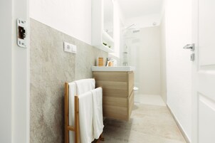 Un baño moderno con tocador de madera, ducha y perchero.