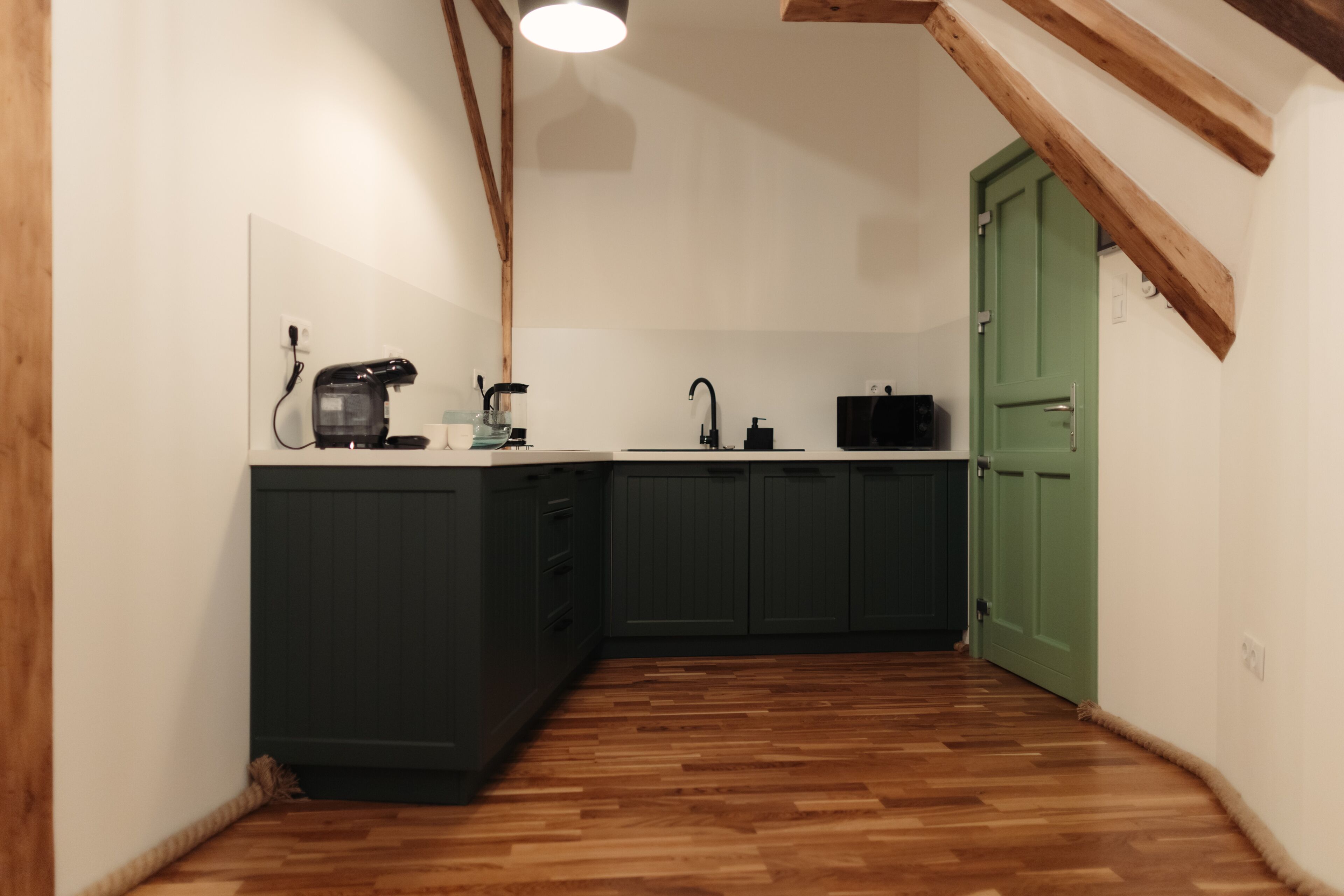 Una cocina compacta con armarios oscuros, encimera de madera y una puerta verde.