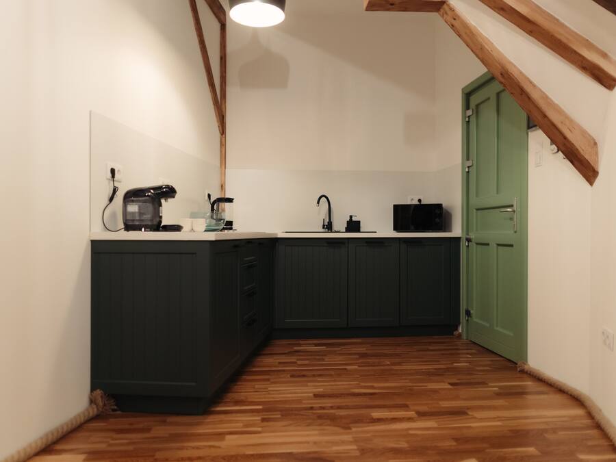 Una cocina compacta con armarios oscuros, encimera de madera y una puerta verde.