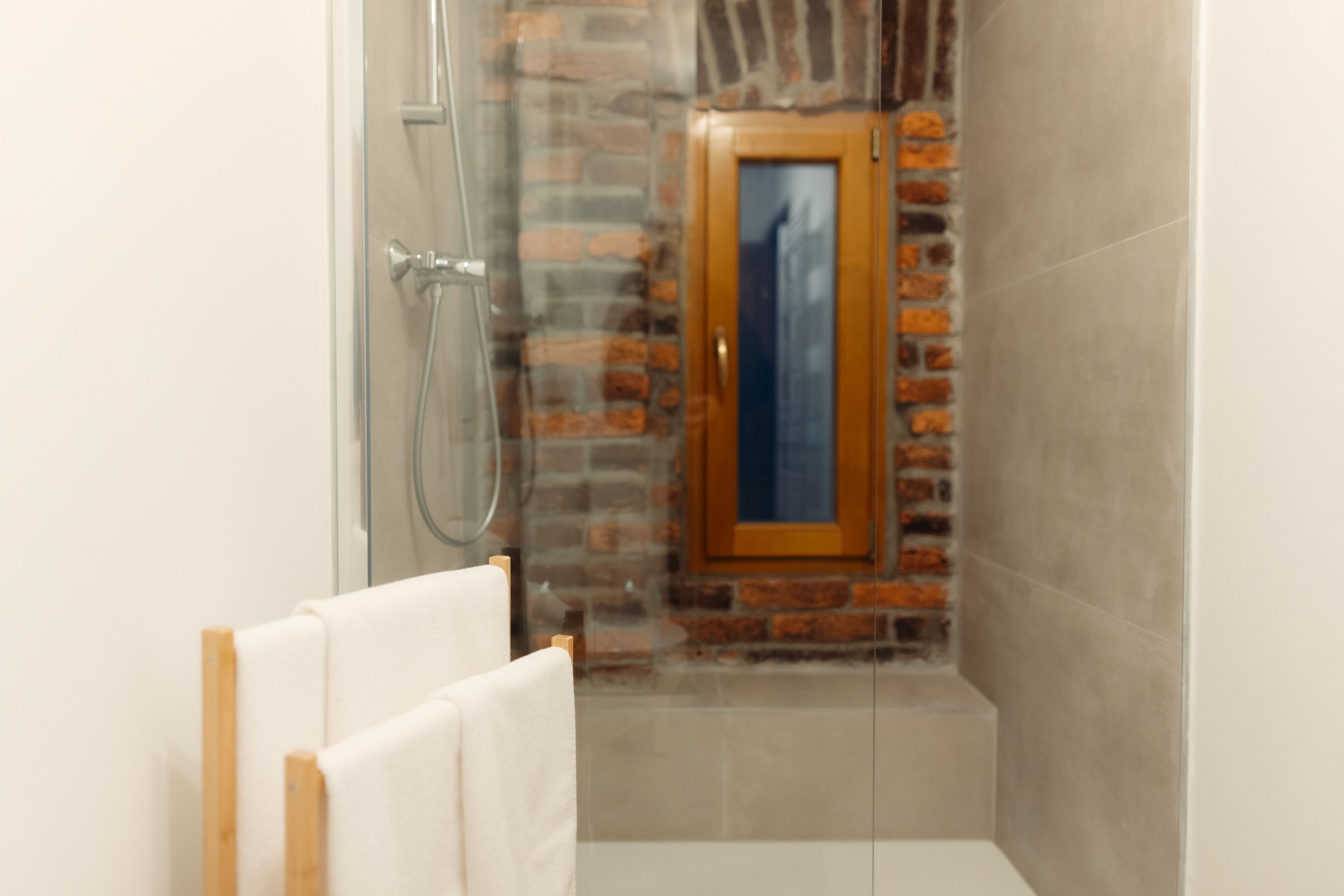 A bathroom with a glass shower enclosure, a wooden door, and a white bathtub.
