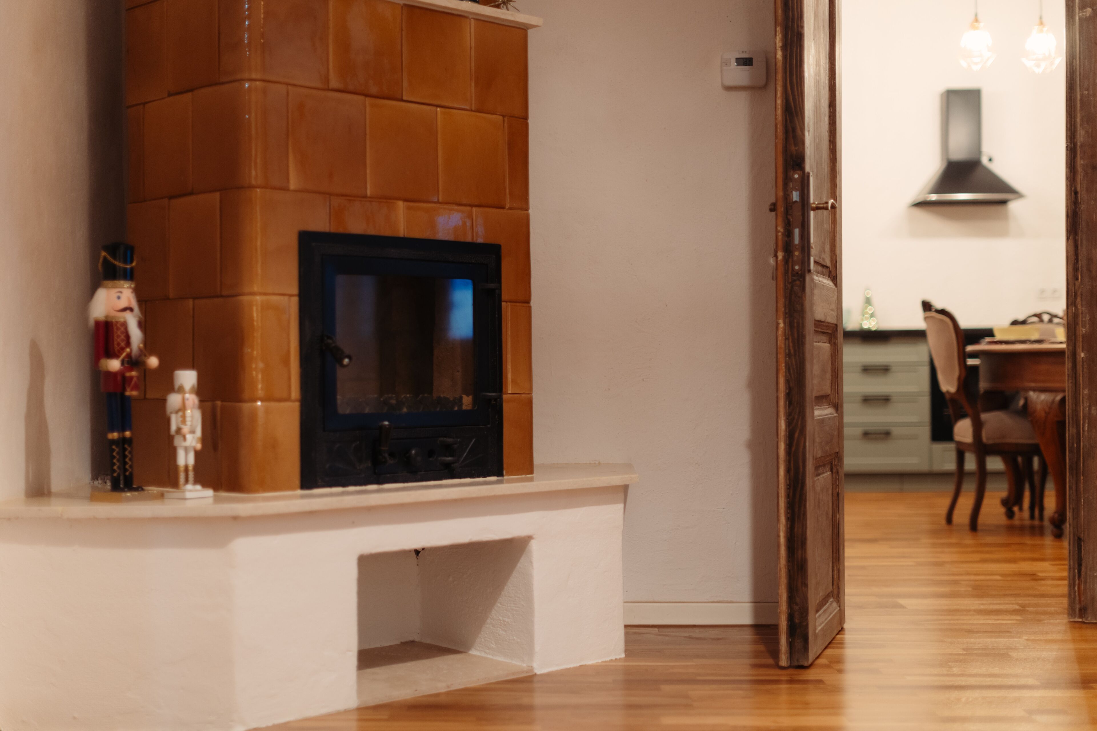 A modern kitchen with a built-in stove, wooden cabinets, and a dining area with chairs and a table.