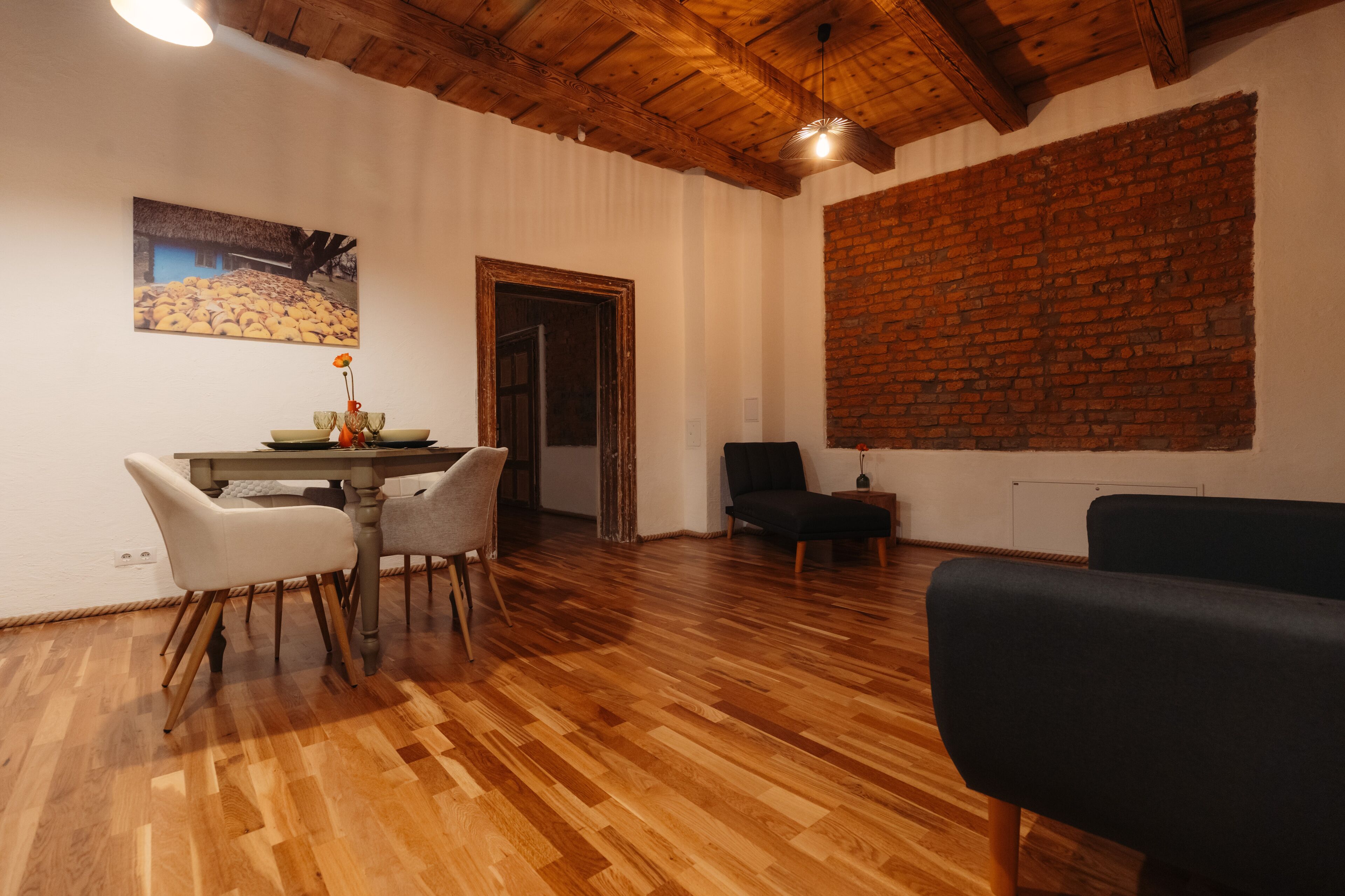 Ein Essbereich mit Holztisch und Stühlen, einer Wand mit Backsteinverkleidung und einer Tür zu einem anderen Raum.