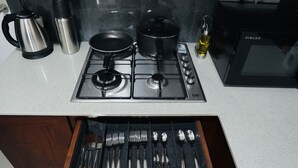 A kitchen with a gas stove, pots, a kettle, and a water bottle.